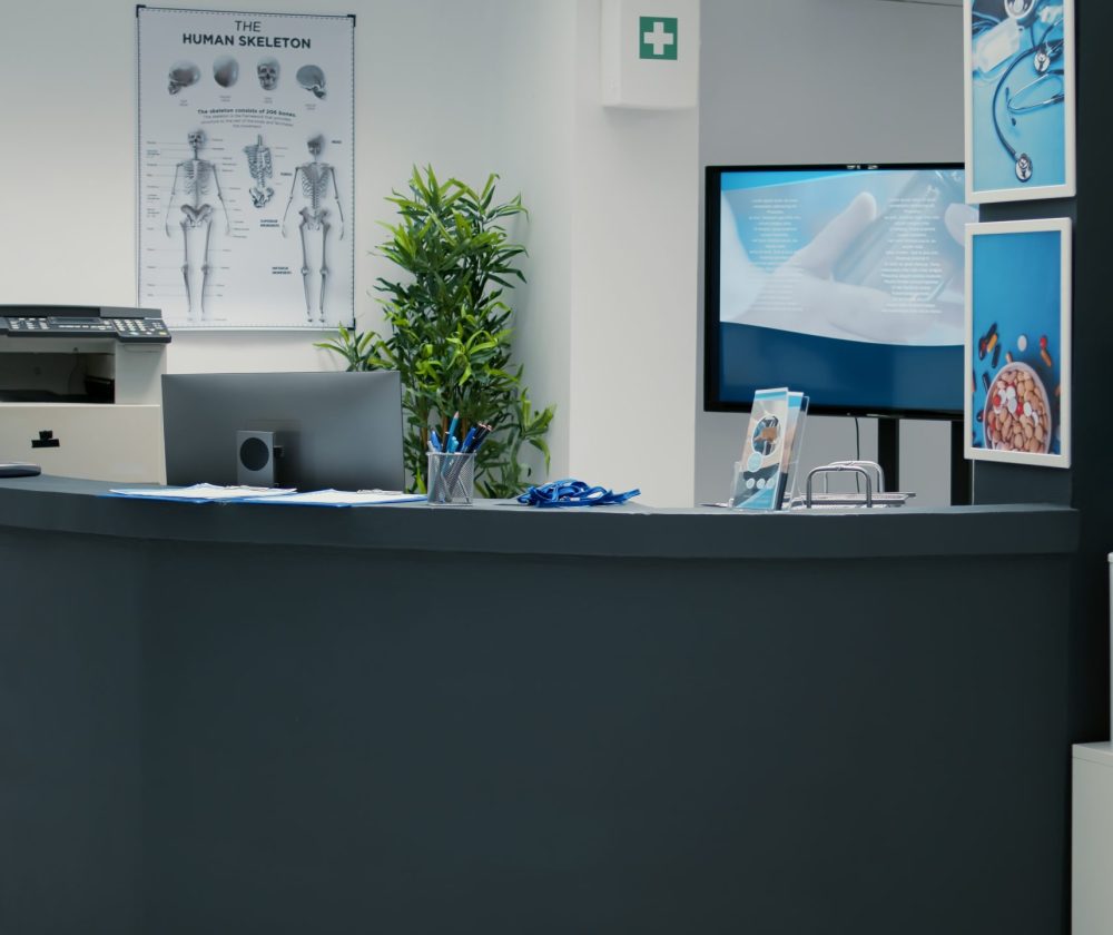 Nobody in empty waiting room lobby with desktop at reception, helping patients with medical insurance to attend checkup visit appointment. Waiting area with counter at hospital.